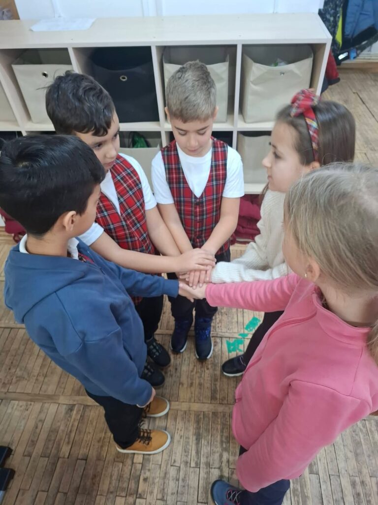 Elevi din ciclul primar strângându-și mâinile într-un gest de prietenie