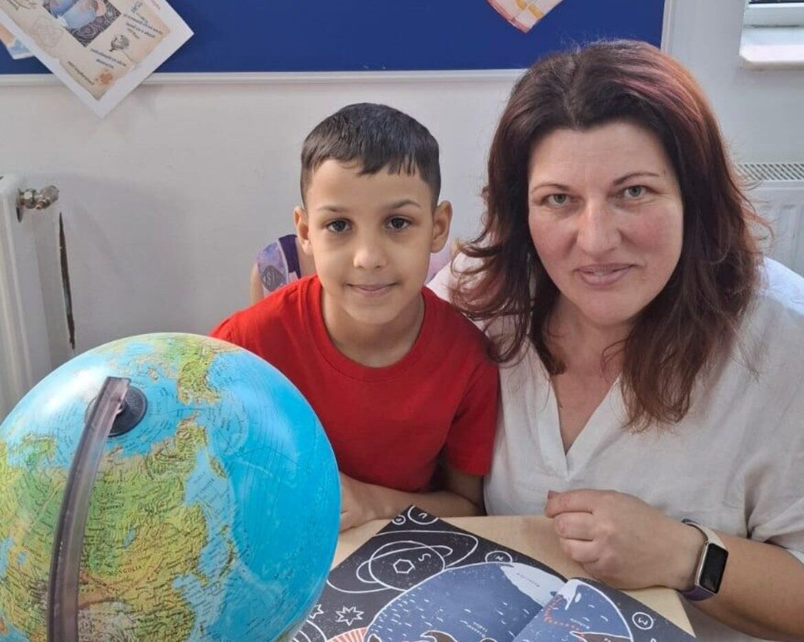 Profesoara Oana Toderoiu cu elevul Eniko, în clasă, cu globul pământesc, explorând povestea „Străbunicul meu, Emil Racoviță”