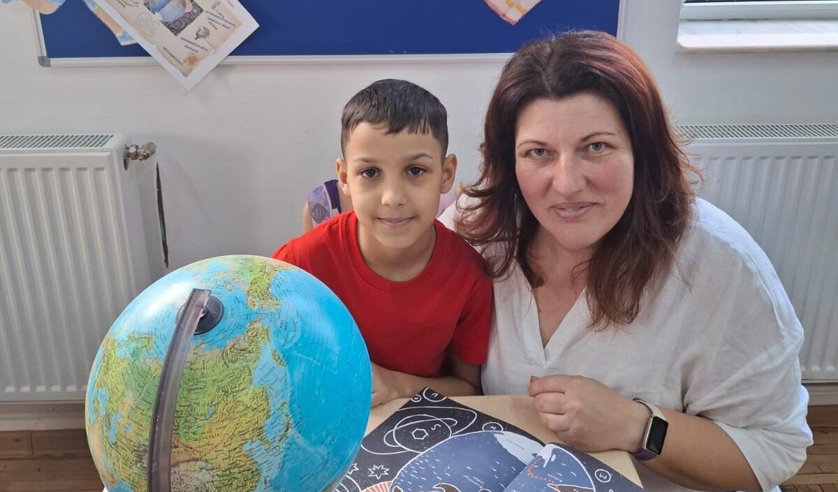 Profesoara Oana Toderoiu cu elevul Eniko, în clasă, cu globul pământesc, explorând povestea „Străbunicul meu, Emil Racoviță”