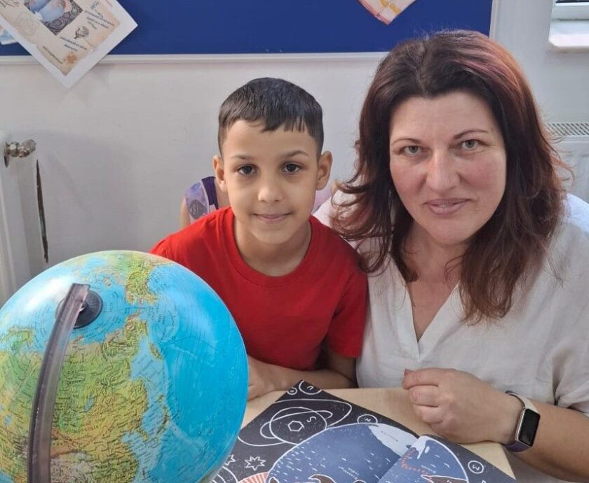 Profesoara Oana Toderoiu cu elevul Eniko, în clasă, cu globul pământesc, explorând povestea „Străbunicul meu, Emil Racoviță”